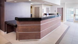 A reception area with a marble counter, a reception desk, and a door leading to a hallway. - Residence Inn By Marriott Dallas Park Central (Dallas)