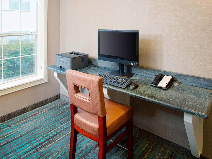 A hotel workspace with a computer, printer, and chair.