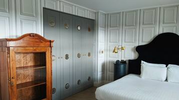 A bedroom with a large bed, a wooden cabinet, a wardrobe with multiple doors, and a bedside lamp.