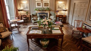 A spacious, elegantly furnished room with a large wooden herringbone floor, a fireplace, and a chandelier. - Pembroke Townhouse (Dublin)