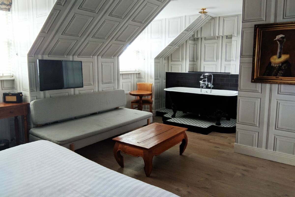A modern interior with a sofa, wooden coffee table, and a kitchen area with a bathtub.