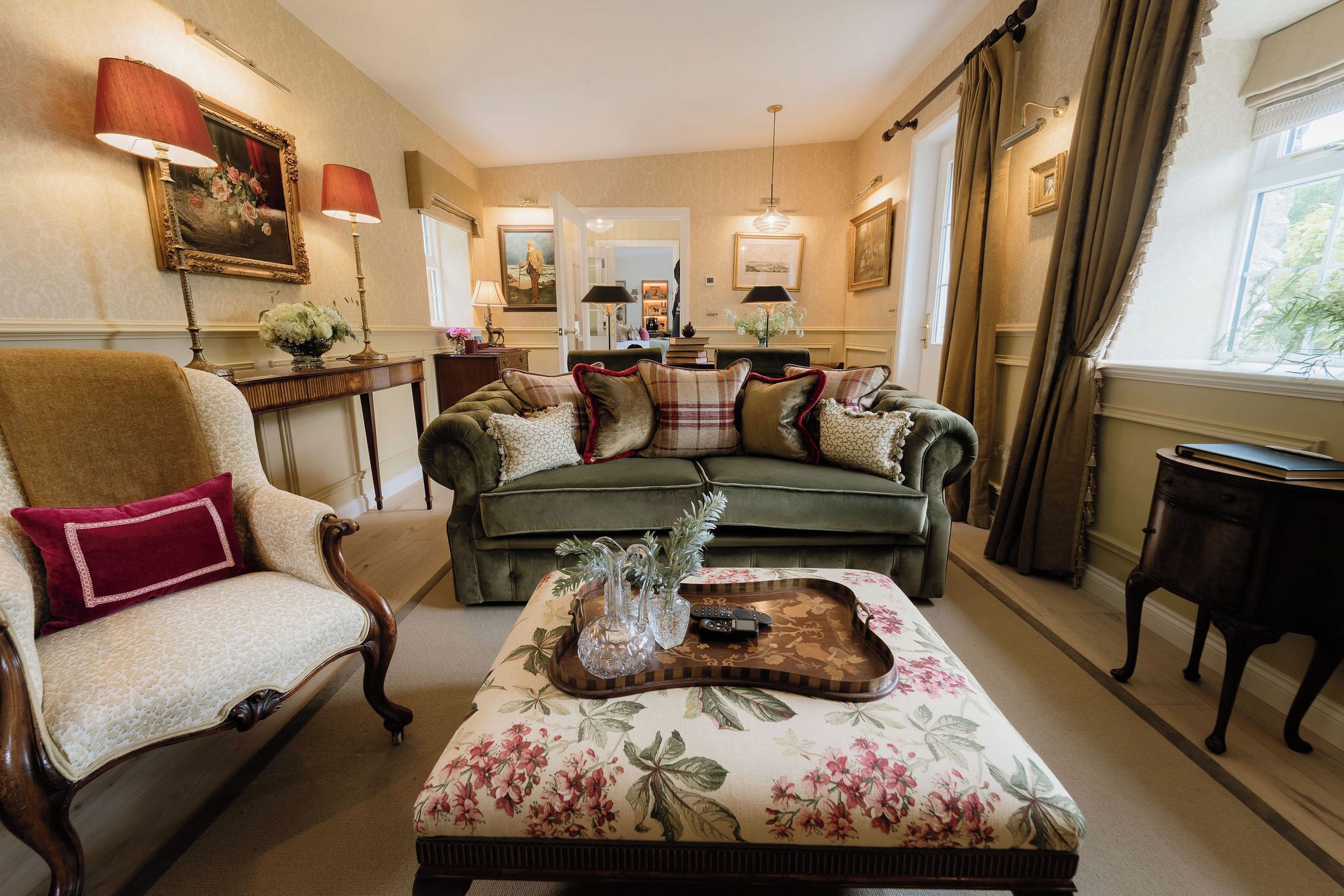 A traditional living room with a sofa, armchair, and ottoman, a wooden coffee table, and a dining area in the background.