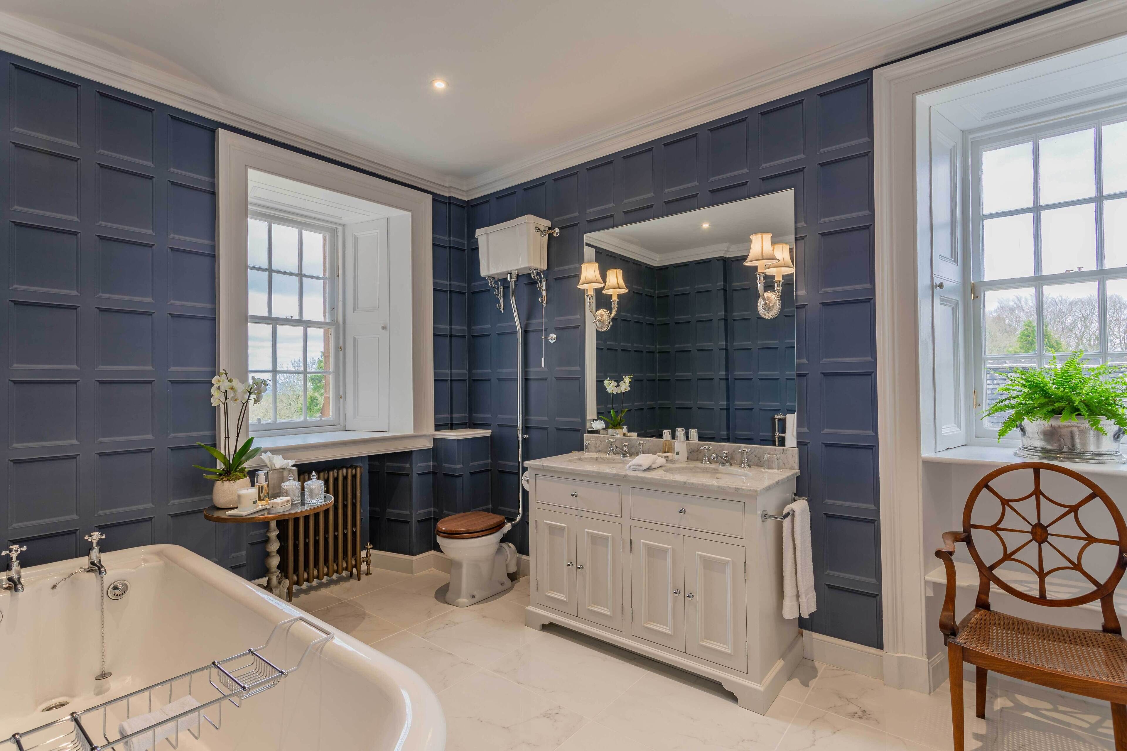 A bathroom with a bathtub, toilet, vanity, and a large mirror.