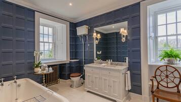 A bathroom with a bathtub, toilet, vanity, and a large mirror.