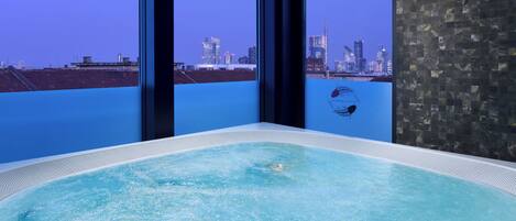 Un jacuzzi con vista a la ciudad a través de amplios ventanales.