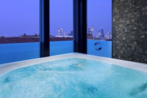 A hot tub with a cityscape view through large windows. - Enterprise Hotel (Milan)