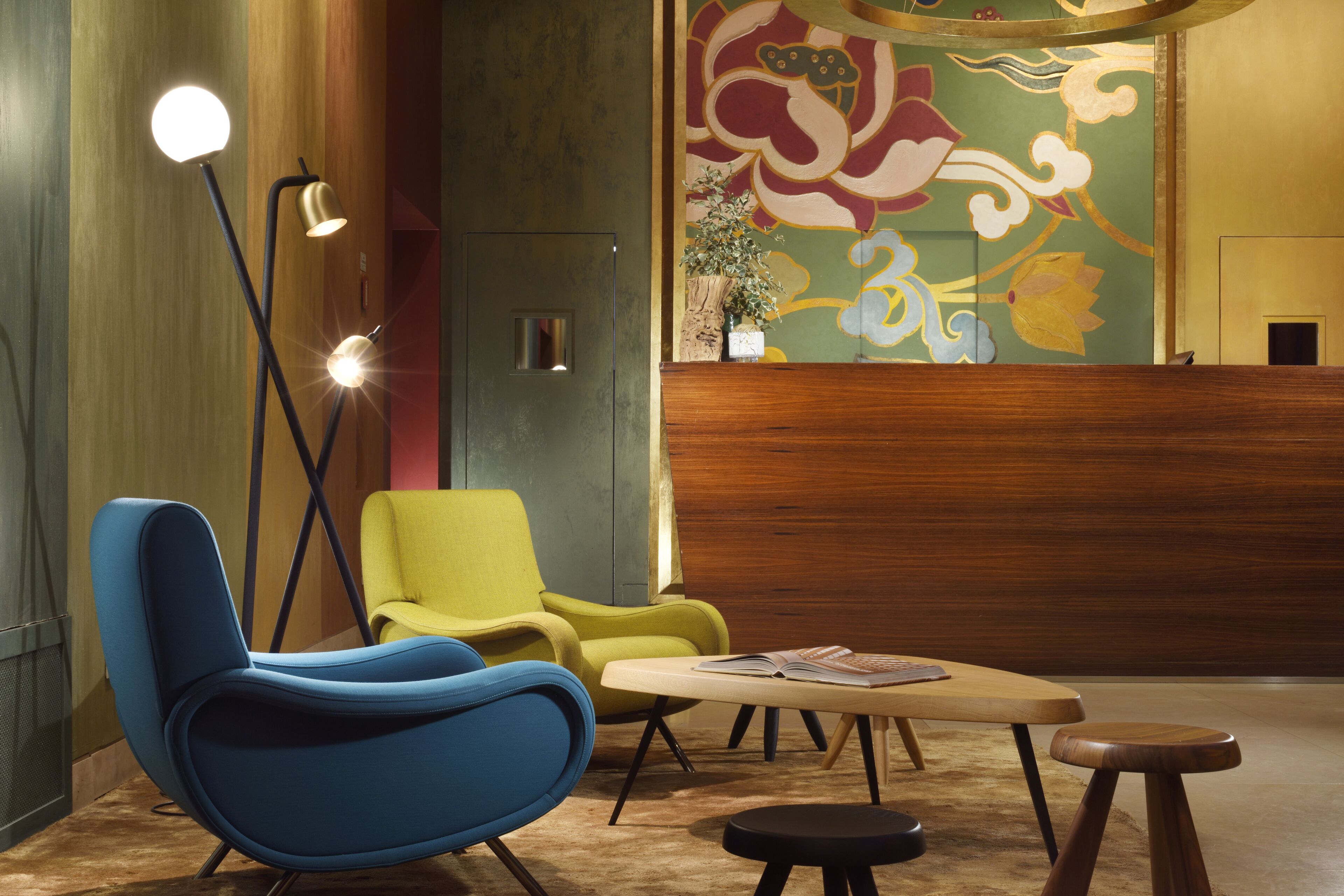 Eine moderne Lobby mit einem blauen Sessel, einem gelben Sessel, einem Holzbüroempfangstresen und einer Stehlampe.