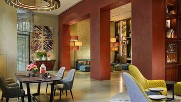 Un lobby moderno con zona de comedor, asientos y estantería.