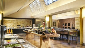 Montaje de bufé con diversos alimentos y una gran mesa de madera en el centro.