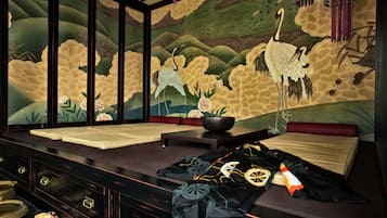 A traditional room with tatami mats, a low table, and a mural of cranes.