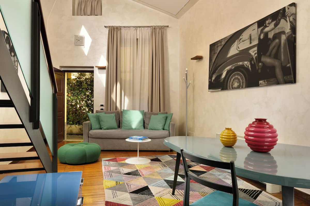 A modern living room with a sofa, a coffee table, a glass table, and a painting on the wall.