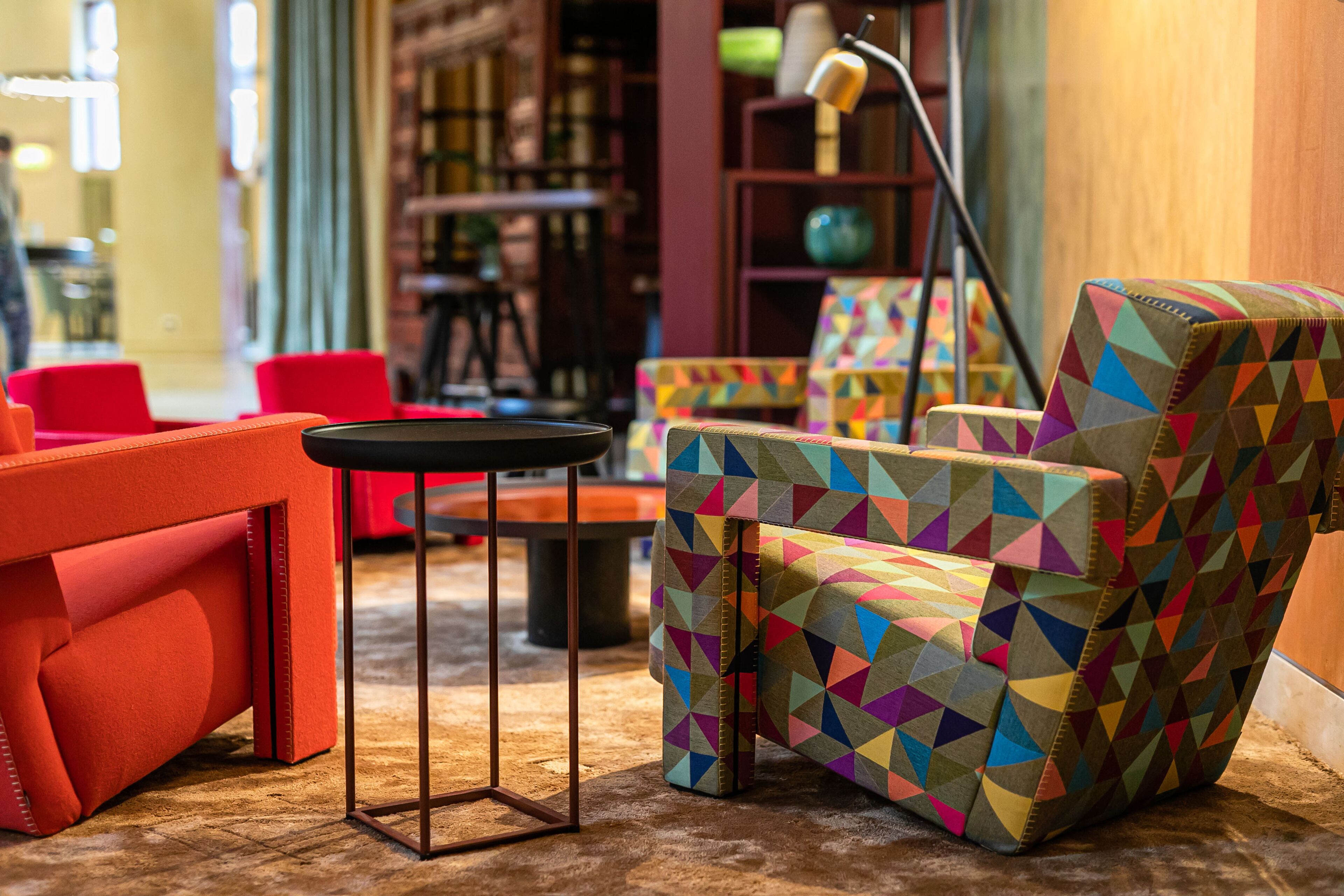 Un espace de détente moderne avec des fauteuils aux motifs géométriques éclatants et un canapé rouge.