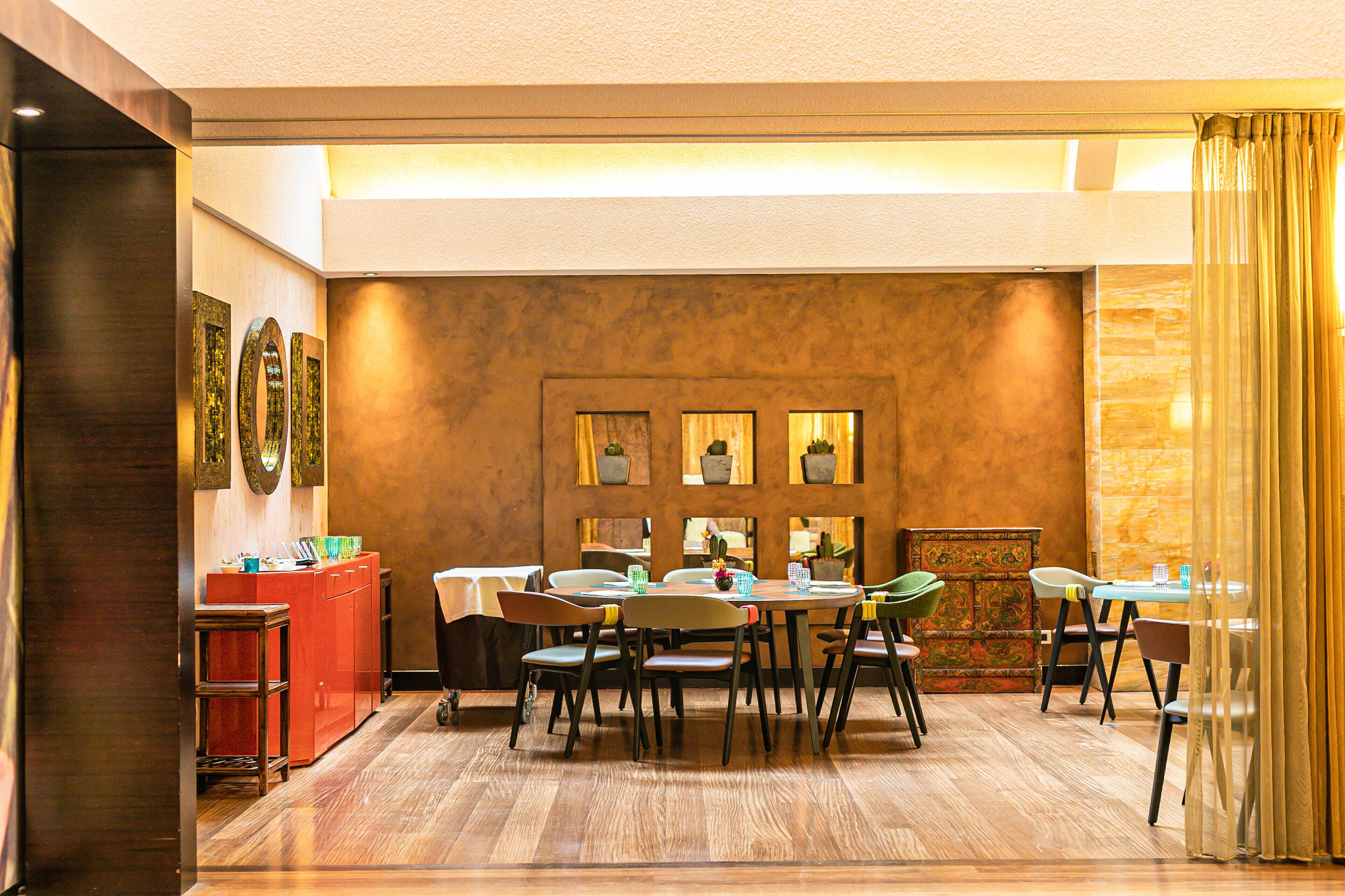 Un comedor con suelo de madera, una recepción y una pared con obras de arte enmarcadas.