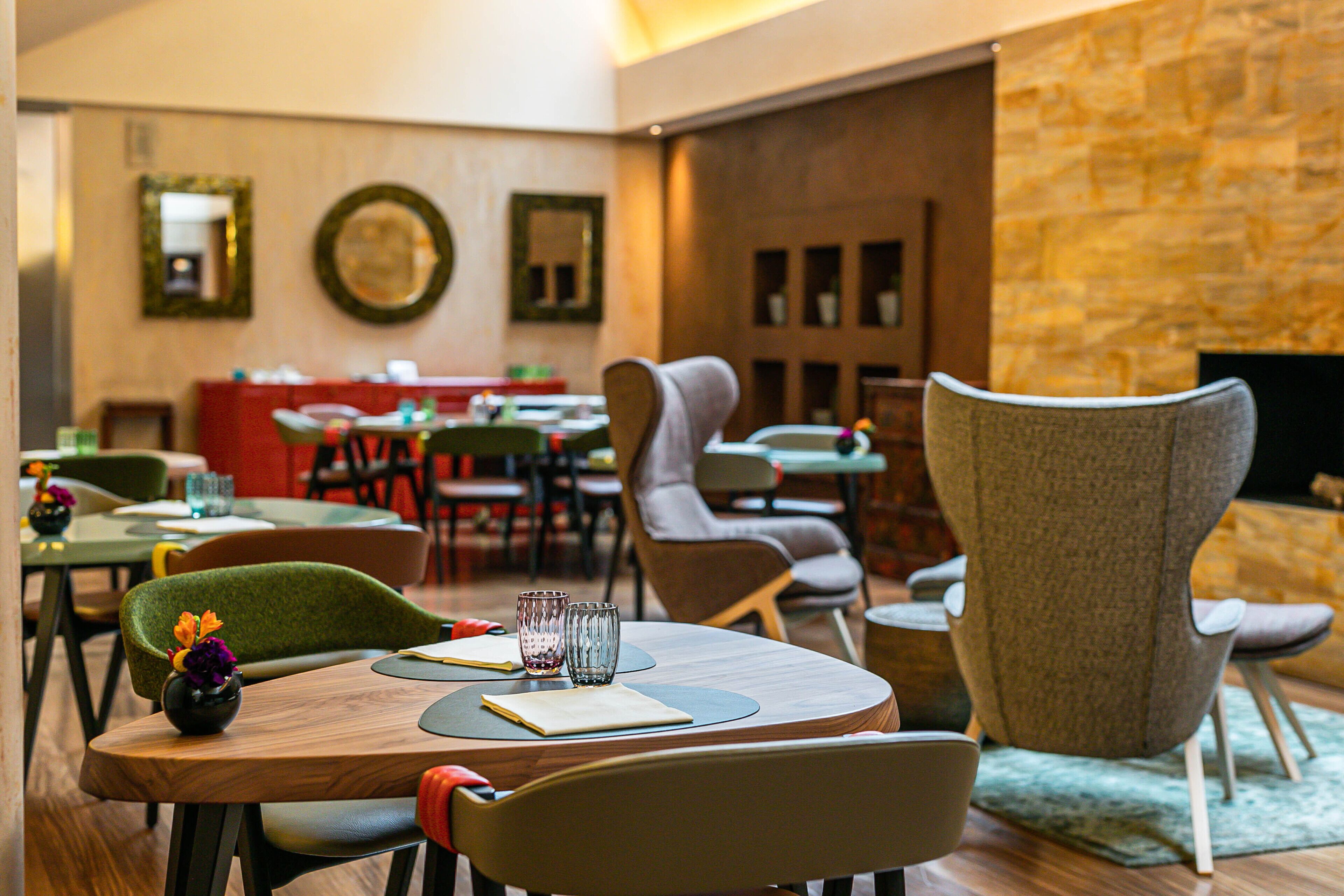 A restaurant with round tables, chairs, and a stone wall.