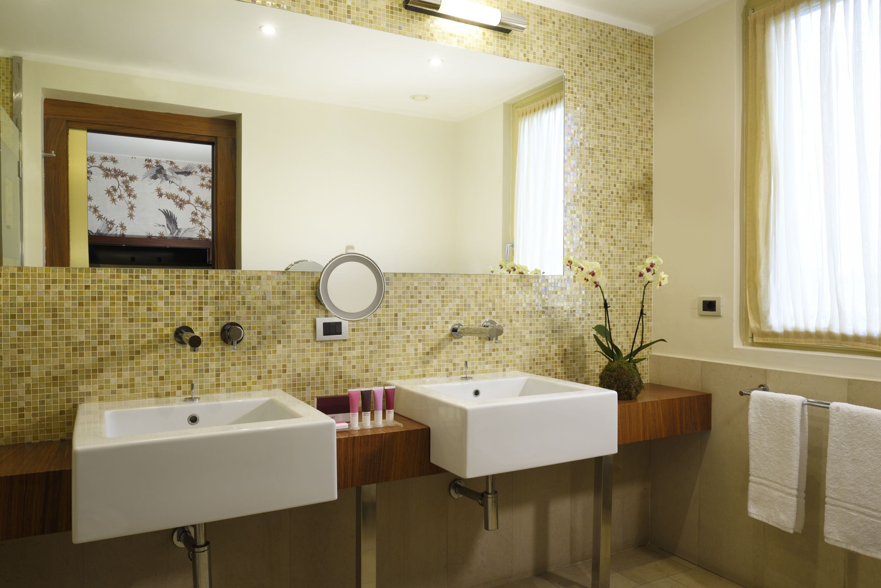 A bathroom with two sinks, a mirror, and a window with curtains.