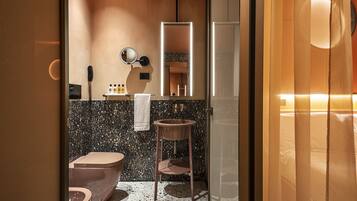 Une salle de bain moderne avec des toilettes sur pied, un lavabo sur colonne et un grand miroir.