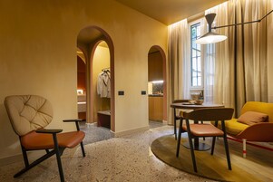 Een moderne hotelkamer met een zithoek, een eettafel en een stadszicht door grote ramen.