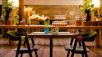 Un restaurante con una larga mesa de madera, dos sillas verdes y una variedad de platos y bebidas sobre la mesa.