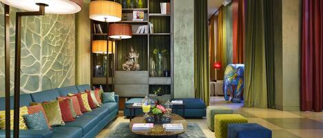 A modern living room with a blue sofa, a coffee table, and a bookshelf.