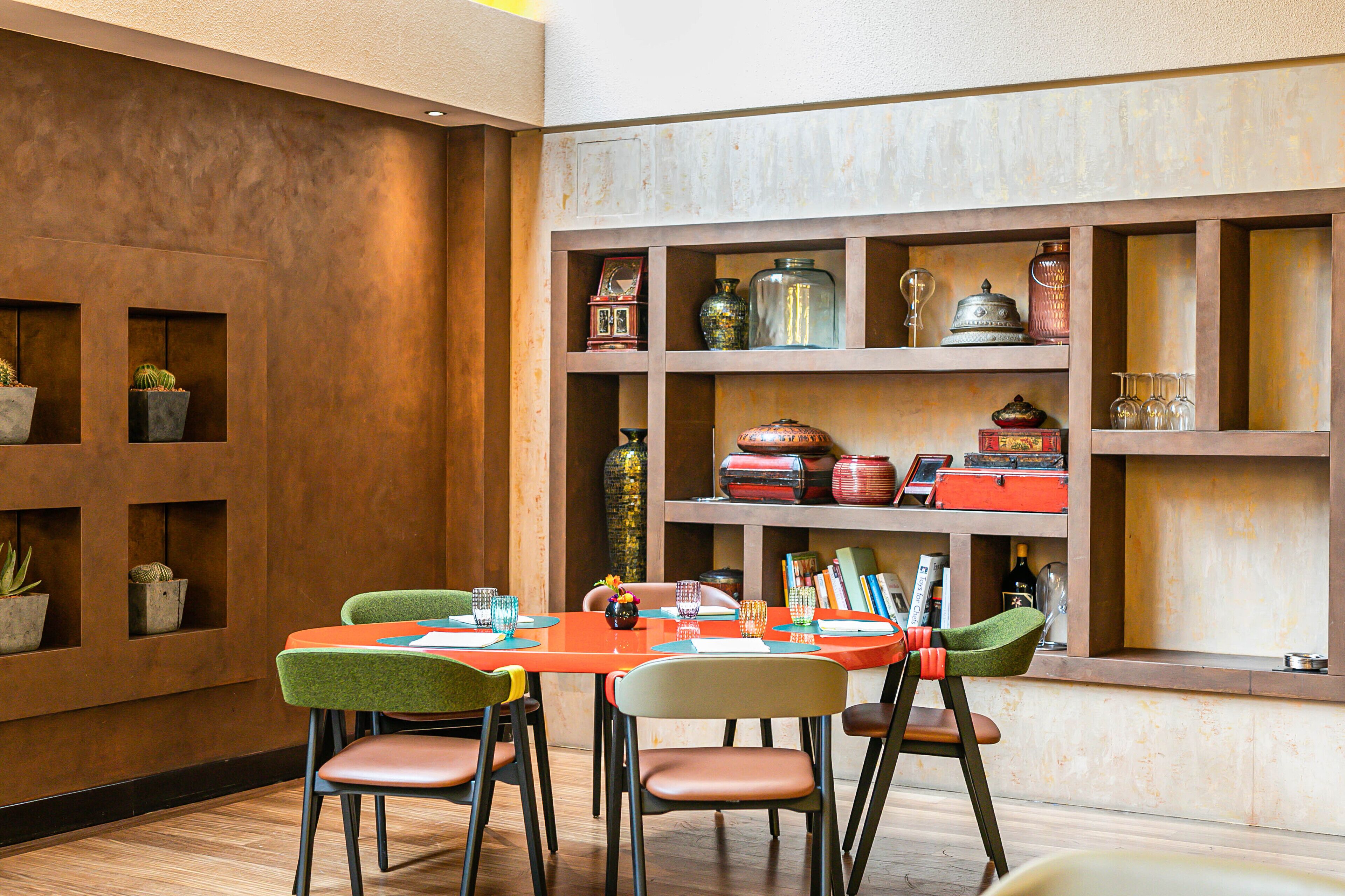 A dining area with a wooden table and chairs, surrounded by shelves with decorative items.