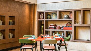 A dining area with a wooden table and chairs, surrounded by shelves with decorative items.