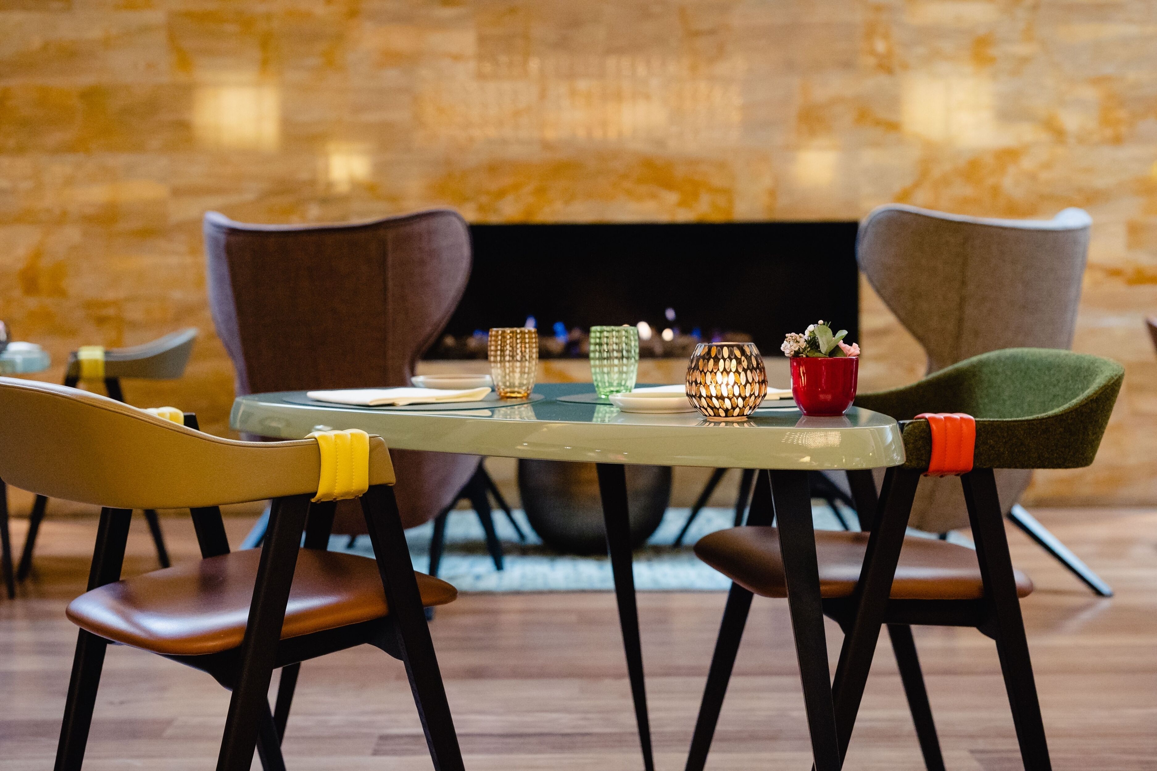 A dining area with a round table, four chairs, and a fireplace in the background.