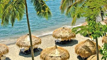 A beach with thatched umbrellas and palm trees.