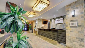 A reception area with a stone wall, a sign for 'Blackcomb Lodge', a reception desk, and potted plants. - Blackcomb Lodge (Whistler)