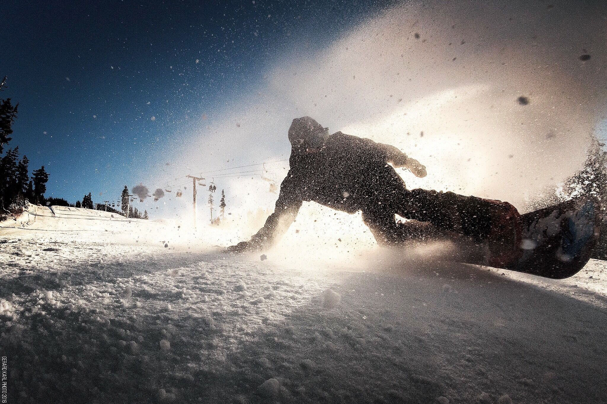 A snowboarder in motion, creating a spray of snow.
