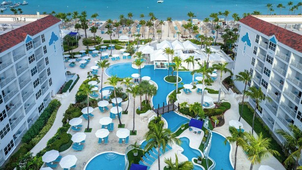 A resort with multiple swimming pools, palm trees, and a view of the ocean.