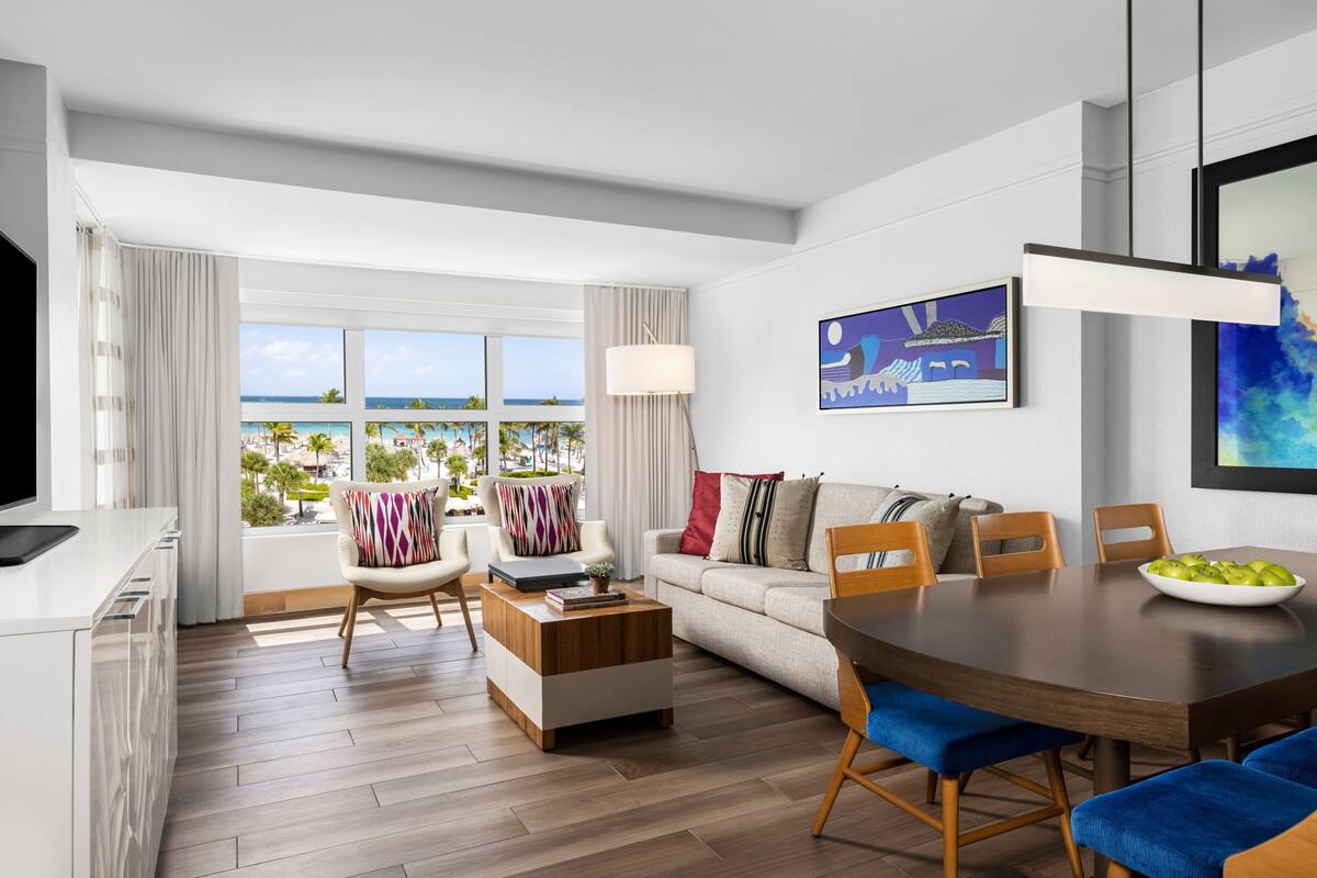 Quarto de hotel moderno com varanda, área de refeições e sala de estar.