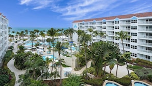 A resort with multiple swimming pools, palm trees, and a view of the ocean.
