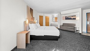Een moderne hotelkamer met een bed, een bank, een klein tafeltje en een tv aan de muur.