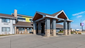 Een modern hotel met een stenen gevel, een overdekte ingang en een helderblauwe lucht.