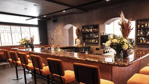 A bar area with a long counter, multiple bar stools, and a variety of bottles and glasses. - Hotel Saint-Sulpice (Montreal)
