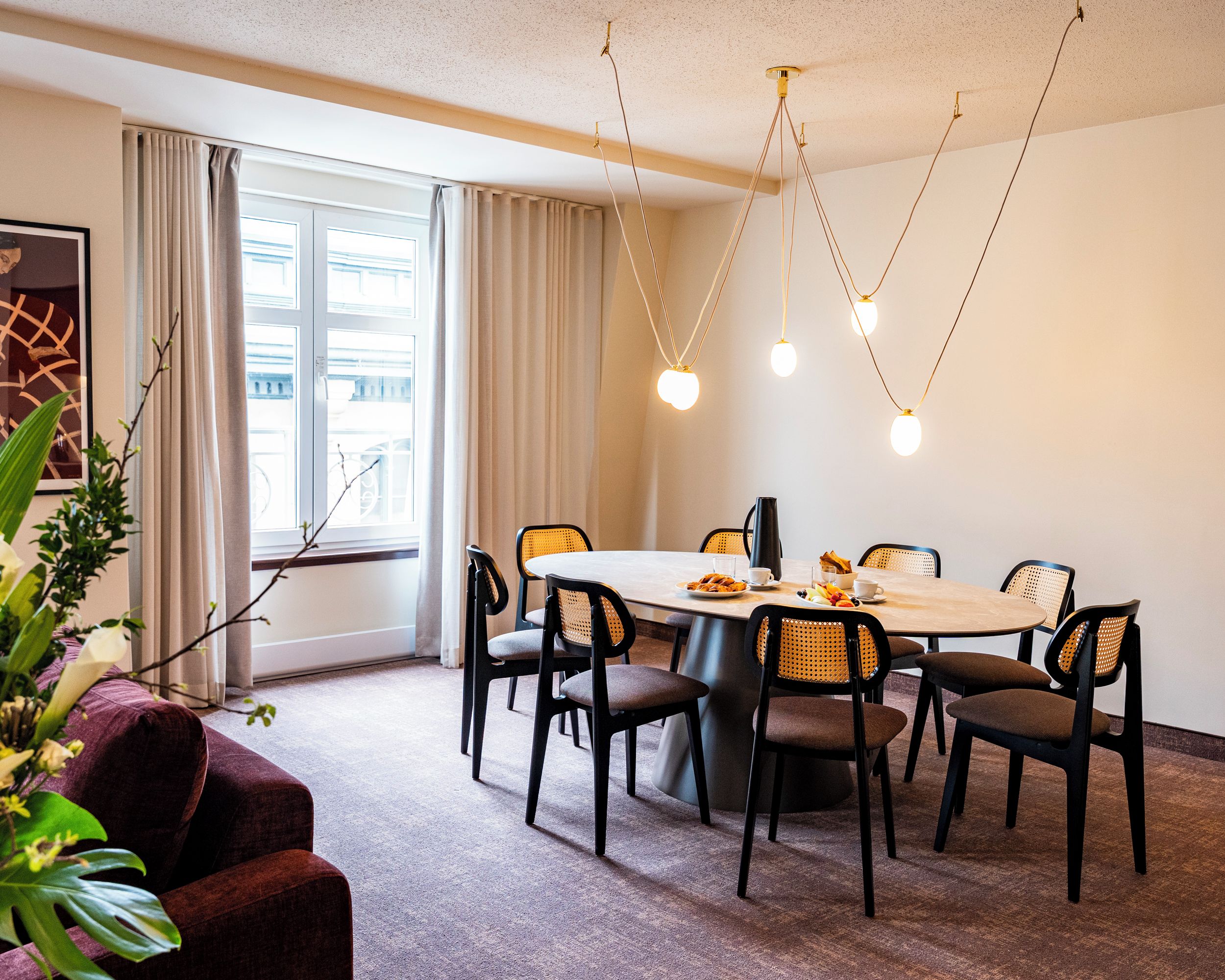 A dining area with a round table, six chairs, and a chandelier.