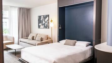 Une chambre d’hôtel avec un grand lit, un canapé, un bureau et une œuvre d’art accrochée au mur.