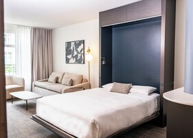 Une chambre d’hôtel avec un grand lit, un canapé, un bureau et une œuvre d’art accrochée au mur.
