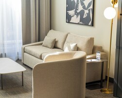 A modern living room with a beige sofa, a matching armchair, a small table, and a floor lamp.
