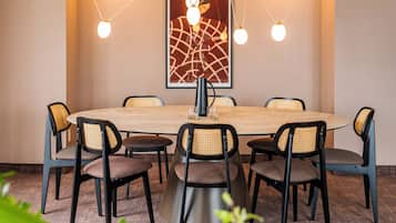 A conference room with a round table, eight chairs, and a modern chandelier.