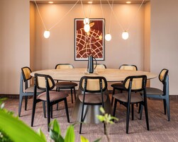 A conference room with a round table, eight chairs, and a modern chandelier.