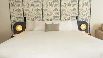 Een bed met hoofdbord waarop een stadsgezicht is afgebeeld, twee nachtlampjes en één sierkussen.