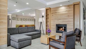 A modern living room with a grey sectional sofa, a wooden coffee table, and a fireplace. - Country Inn & Suites by Radisson, Oklahoma City at Northwest Expressway, OK (Oklahoma City)