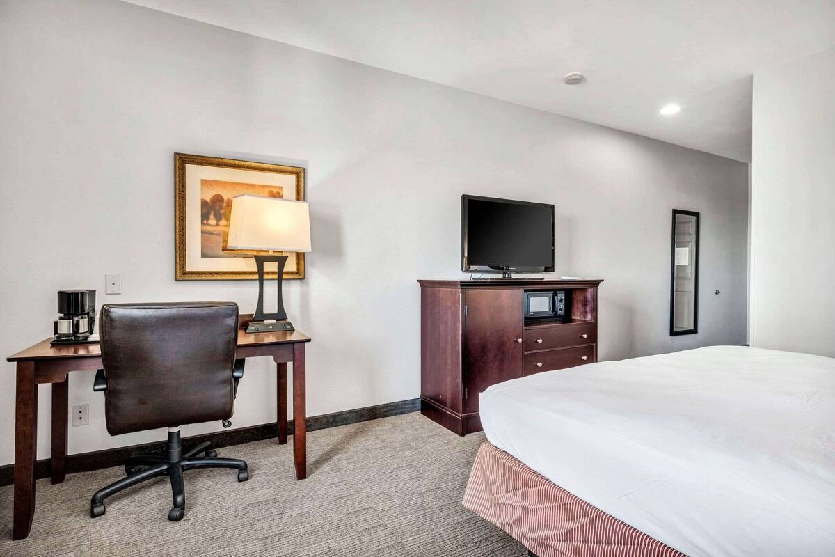 Une chambre d’hôtel comprenant un lit, un bureau avec une chaise, une télévision et une commode.