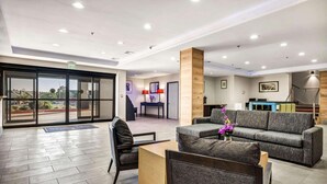 A modern hotel lobby with a reception desk, seating area, and large windows offering a view of the outdoors. - Country Inn & Suites by Radisson, Oklahoma City at Northwest Expressway, OK (Oklahoma City)