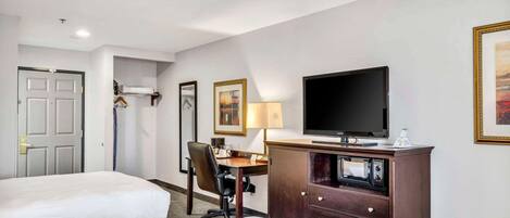 A hotel room with two beds, a desk, a television, a lamp, and a wardrobe.