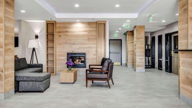 A spacious lobby with a fireplace, seating area, and wooden paneling. - Country Inn & Suites by Radisson, Oklahoma City at Northwest Expressway, OK (Oklahoma City)
