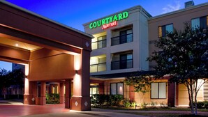 Un hotel Courtyard Marriott con una fachada moderna, varios balcones y una entrada bien iluminada.