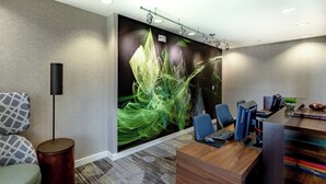 Una oficina moderna con un mural grande en la pared, un escritorio de madera y un área de descanso confortable.