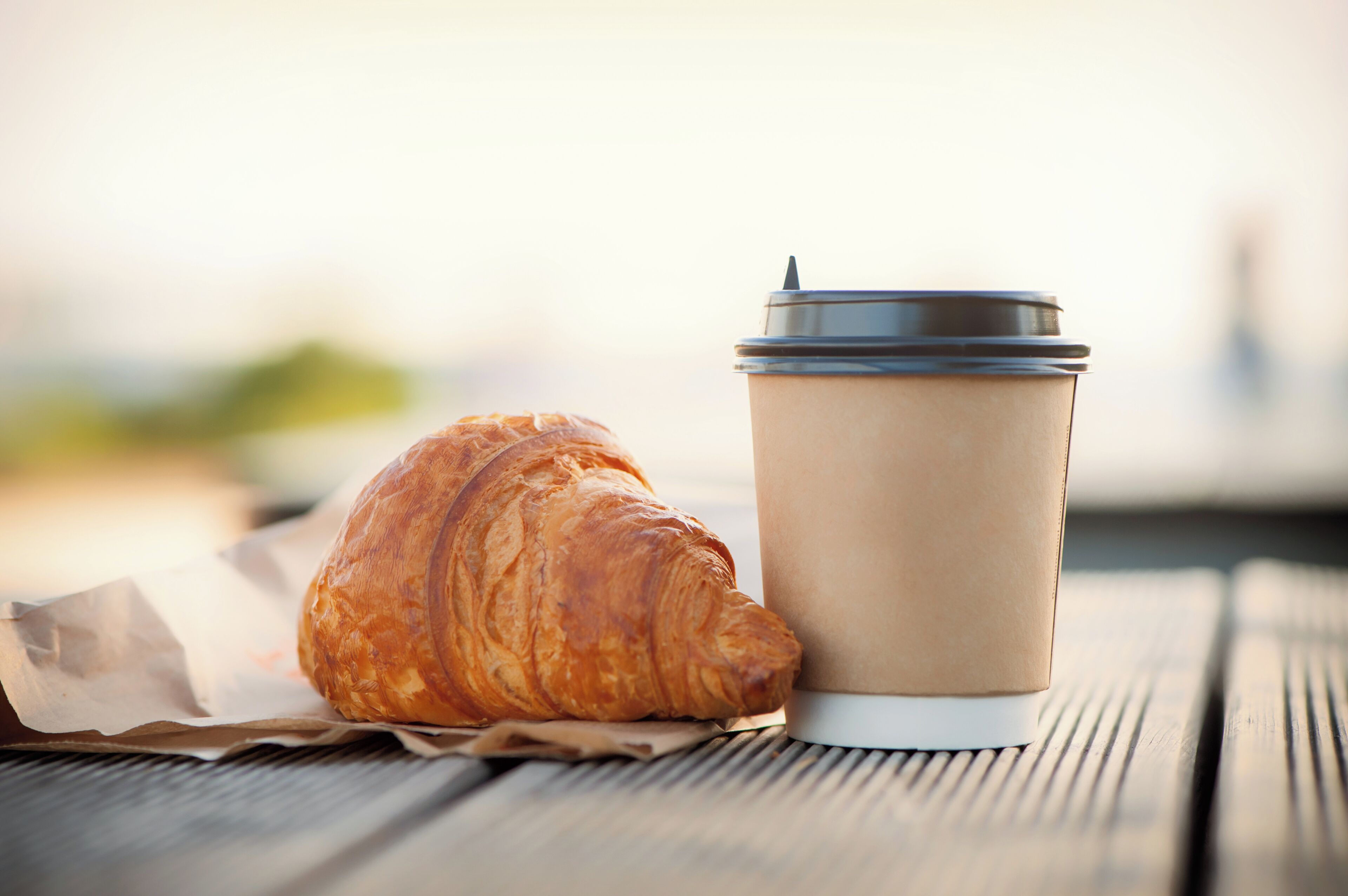Un croissant y una taza de café sobre una mesa de madera.